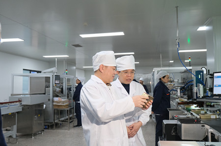 曹智刚(左一)查看公司新增的全自动包装生产线。_副本